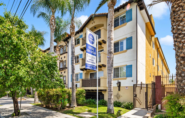 an apartment building with palm trees and a blue and white street sign