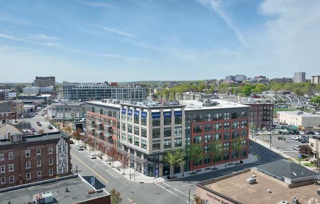 A city street with a large building in the middle and cars parked on the side.