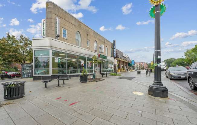 A street view with a building on the left and a pole with a flower on top on the right.