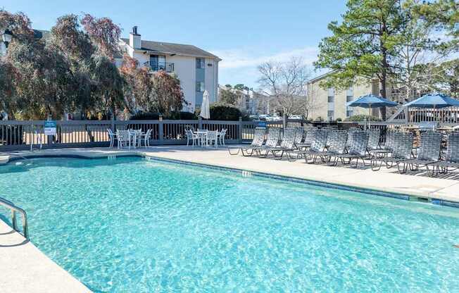 A large swimming pool with chairs around it.