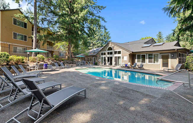 A pool area with sun loungers and a building in the background.