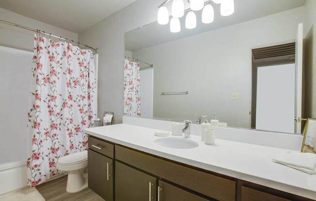A bathroom with a white counter and a floral shower curtain.