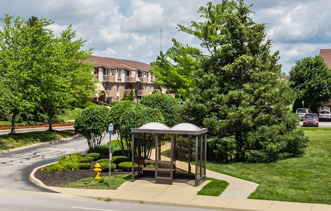 A bus stop with a bench and a yellow fire hydrant in front of a building.