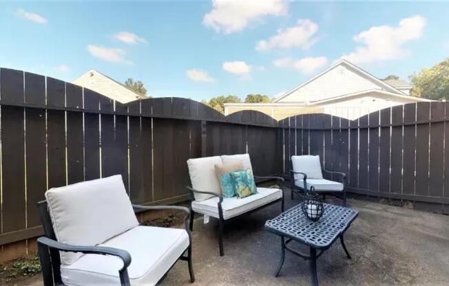 A patio with a white chair and a black table.