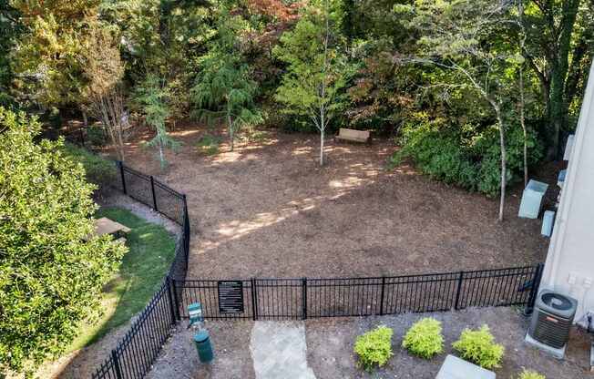 A backyard with a black fence and a green trash can.