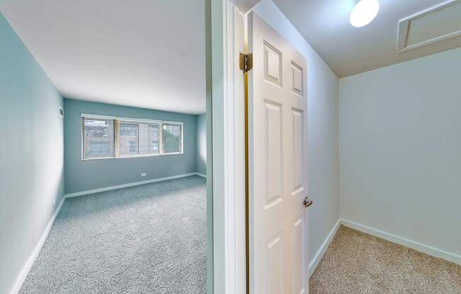 A bedroom with a carpeted floor and a white door.