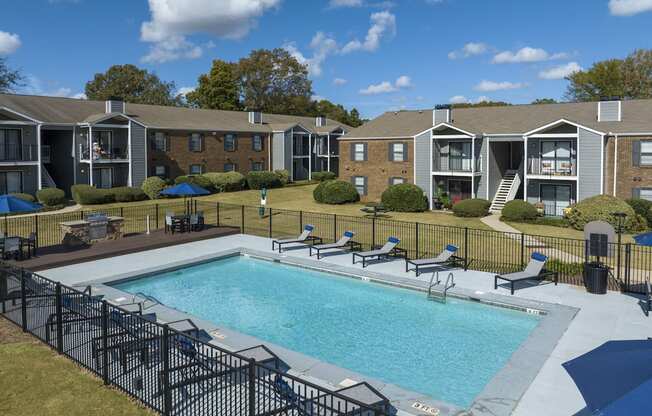 A pool surrounded by chairs and a fence.