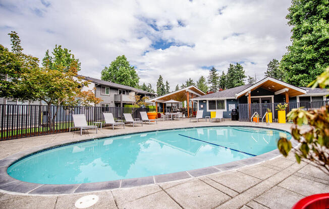 A swimming pool surrounded by trees and chairs.