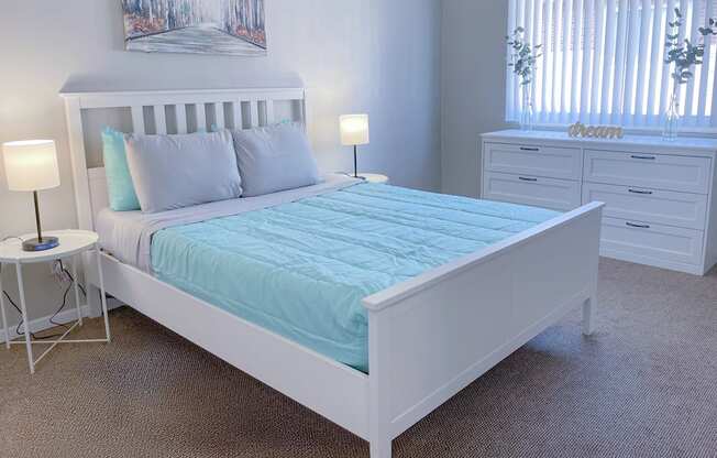 A bedroom with a bed, nightstands, and a painting on the wall.