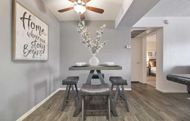 a dining area with a table and chairs and a ceiling fan