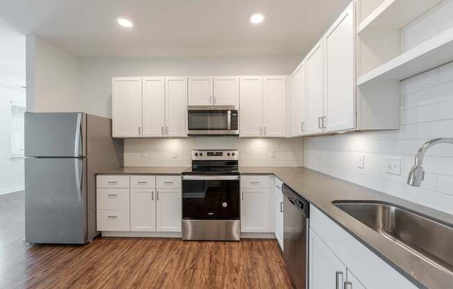 A modern kitchen with white cabinets and stainless steel appliances.