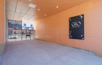 A sign for GIO is on the wall in a parking garage.