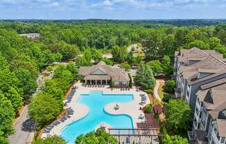 A large swimming pool surrounded by trees and resident clubhouse