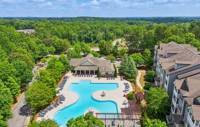 A large swimming pool surrounded by trees and resident clubhouse
