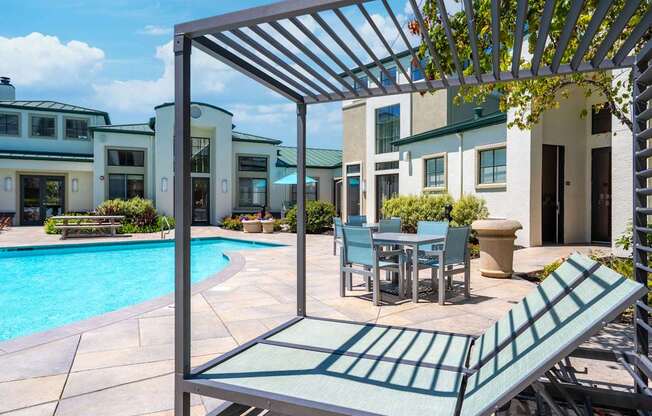 A patio with a table and chairs under a pergola.