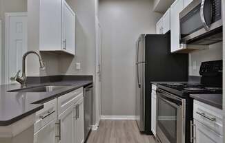 A kitchen with black appliances and white cabinets.