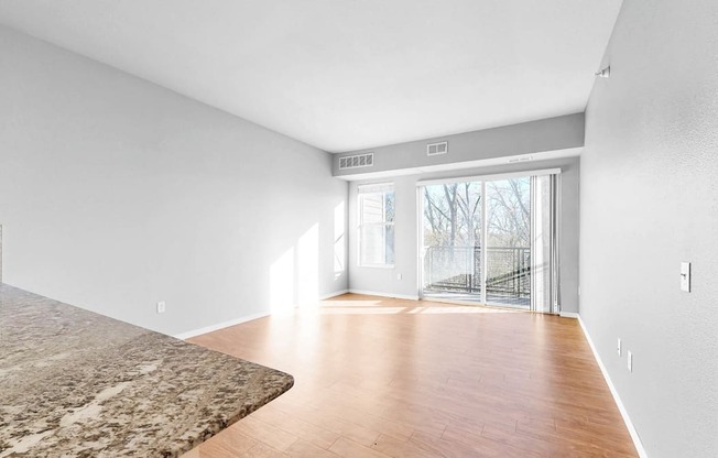 A room with a marble floor and wooden flooring leading to a glass door.