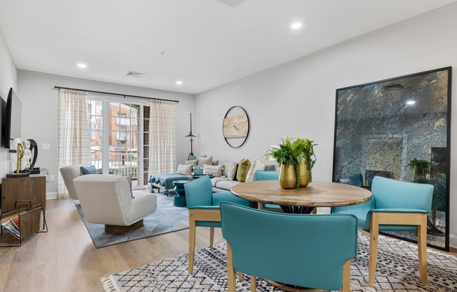 A living room with a large painting on the wall and a dining table with chairs around it.