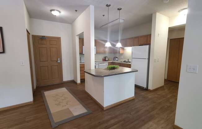 a kitchen and living room with white walls and wood flooring