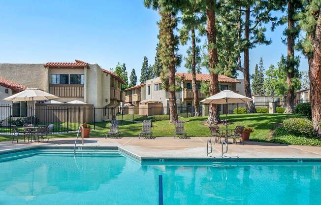 A swimming pool in a backyard with a house and trees in the background.