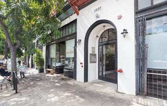 a white building with an arched doorway on a city street at Del Mor Apartments, Los Angeles, 90026