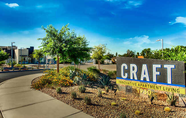 A sign for Craft Apartment Living stands in front of a building.