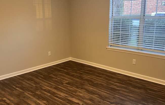 an empty living room with wood floors and a window