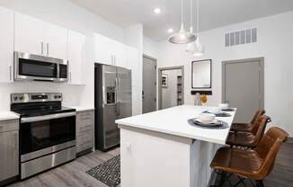 A modern kitchen with a white island and stainless steel appliances.