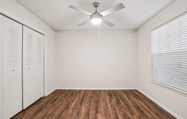 A room with a ceiling fan and wooden flooring.