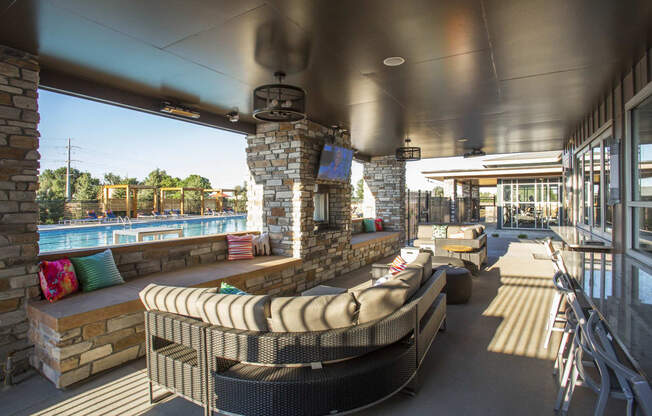 Furnished outdoor lounge area next to pool, with sectional couch and television