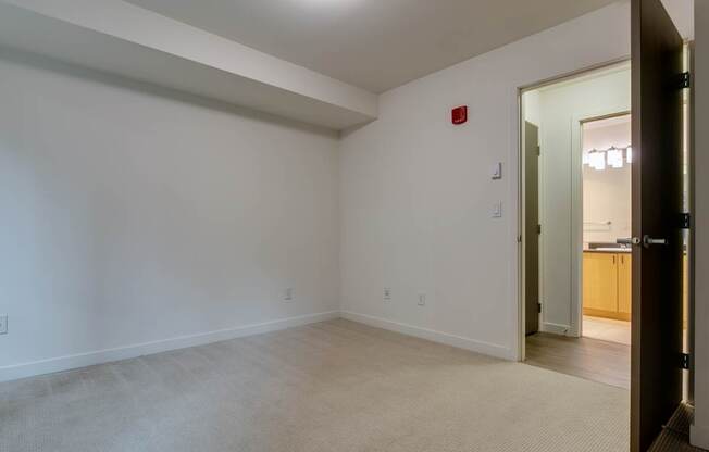 A room with a white wall and a red fire alarm.