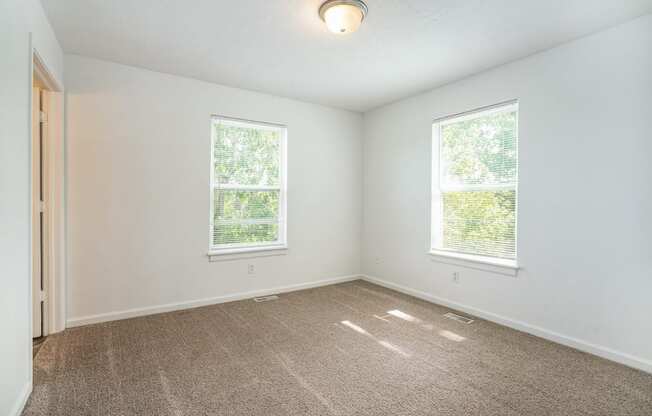 a bedroom with two windows and a carpeted floor