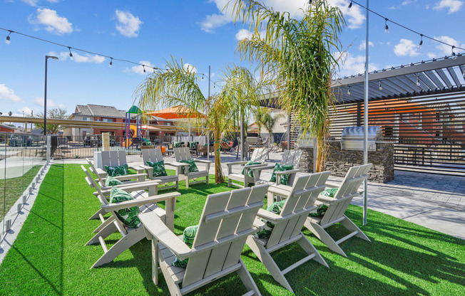 A row of white chairs are lined up on a green lawn.