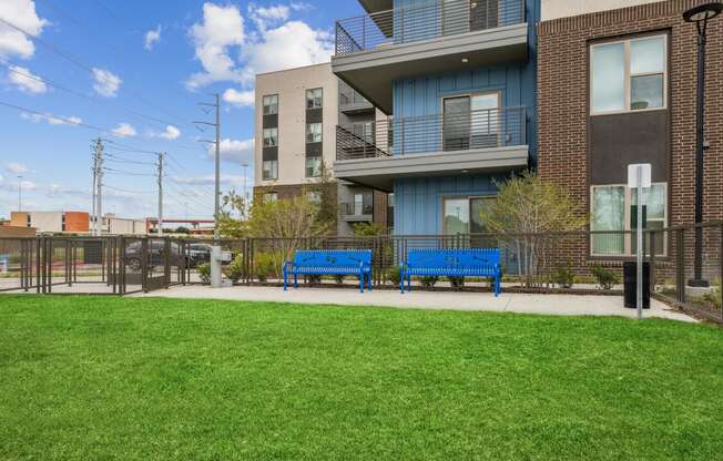 two blue benches in front of an apartment building with a green lawn