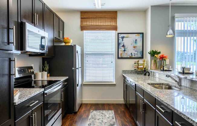 A kitchen with black cabinets and granite countertops.