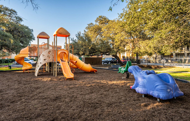 A playground with a yellow and orange slide and a blue slide.