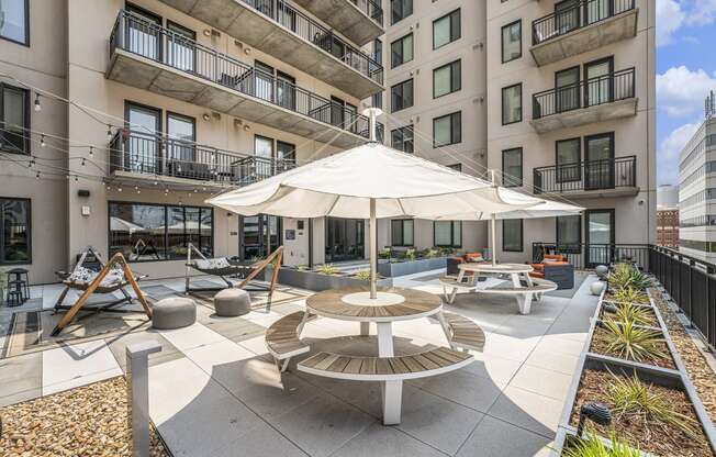 an outdoor patio with tables and an umbrella in an apartment building