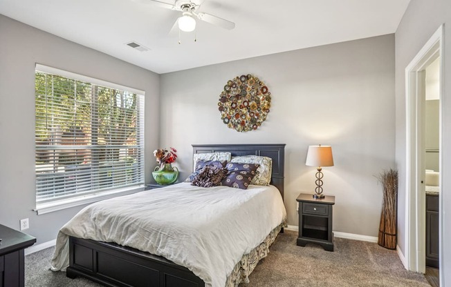 A bedroom with a bed, nightstand, and window.