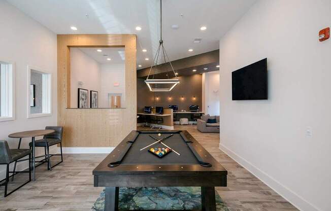 A billiard table is in the middle of a room with a chair and a mirror.