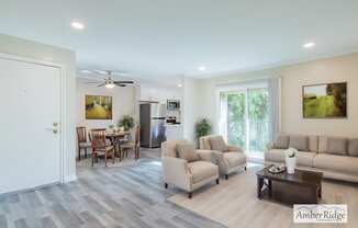 A spacious living room with a dining area and a kitchen in the background.
