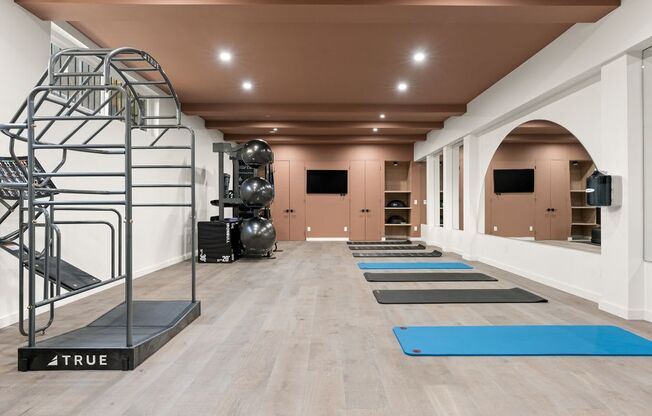 A gym with a variety of equipment including a treadmill, weights, and a climbing wall.
