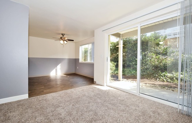 an empty living room with a sliding glass door and a ceiling fan