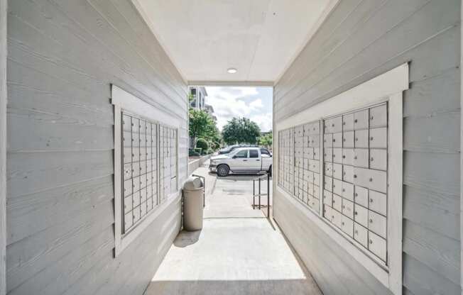 a parking garage with white wood walls and mailboxes and a white car parked outside at St. Augustine Estate, Dallas, TX