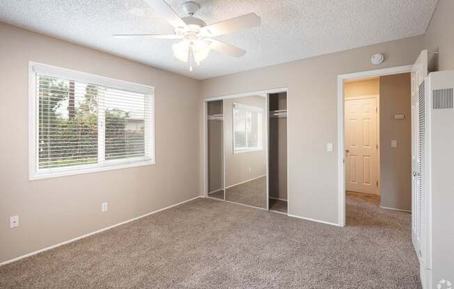 A room with a ceiling fan and a window with blinds.