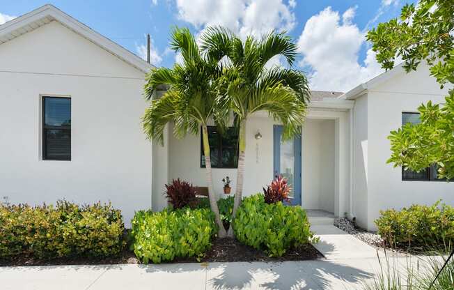 a white house with a palm tree in front of it at Odyssey, Florida, 33905