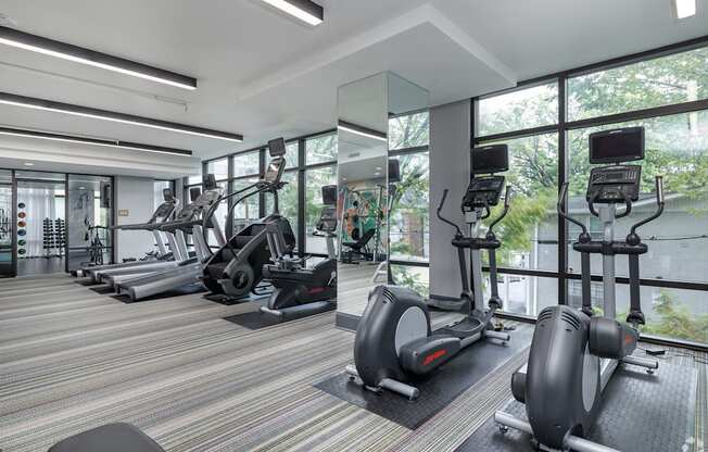 a gym with cardio equipment and floor to ceiling windows