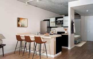 a kitchen and a living room with a bar and stools