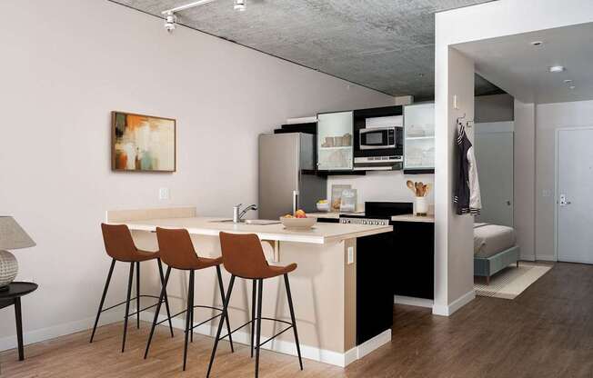 a kitchen and a living room with a bar and stools