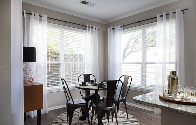 City Place at Westport - Furnished Dining Room With Circular Table, Chairs, and Windows With Blinds and Curtains