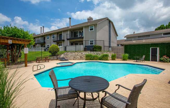 A small round table is surrounded by chairs in a backyard.